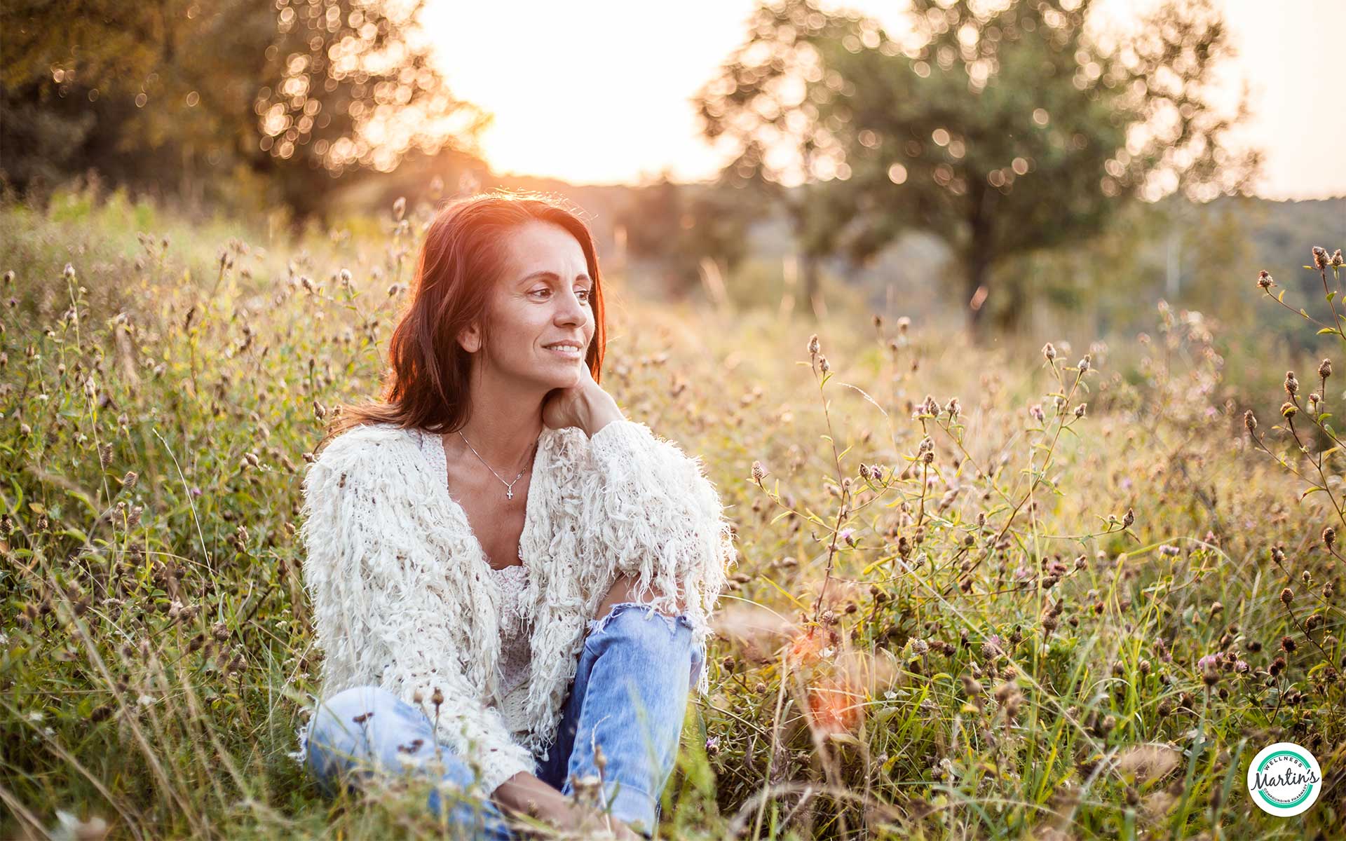 A woman sitting in a grass field smiling