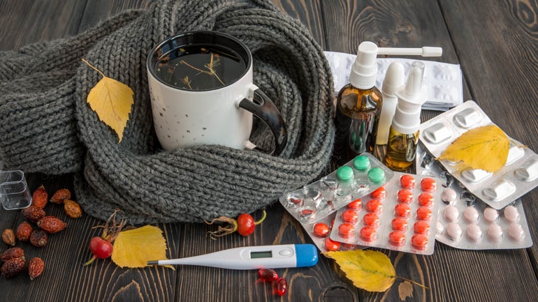 Flu medicine, pills, thermometer, and warm tea