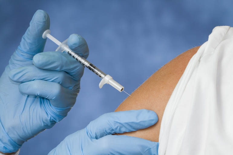 hand administering a flu shot on a person’s arm