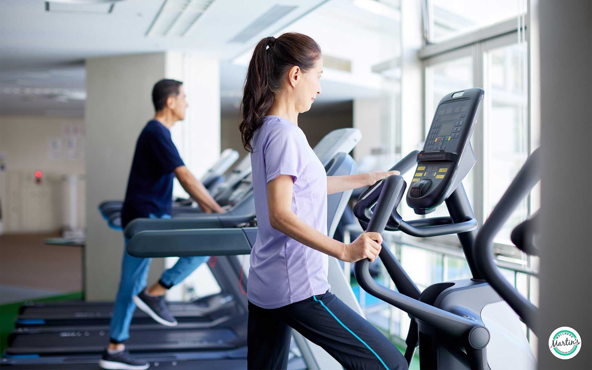 A brunette woman in a purple T-shirt stands on a treadmill, adjusting the screen as she begins an NAD+ boosting workout