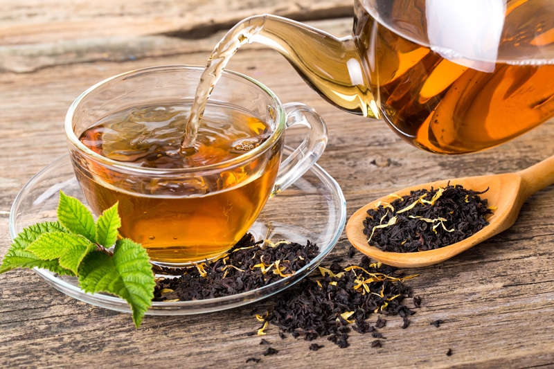 A glass teapot pouring a steaming cup of antioxidant-rich, loose leaf tea