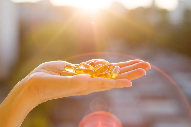 A hand holding supplement capsules used to enhance GAD Enzymes