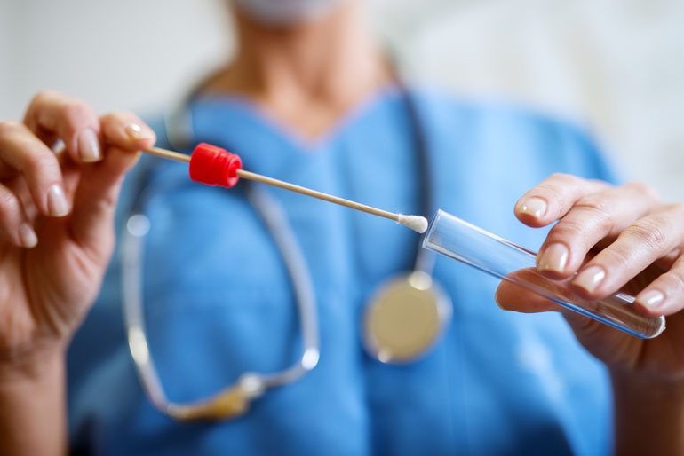 a nurse putting a saliva swab into a test tube for a saliva cortisol/DHEA test.